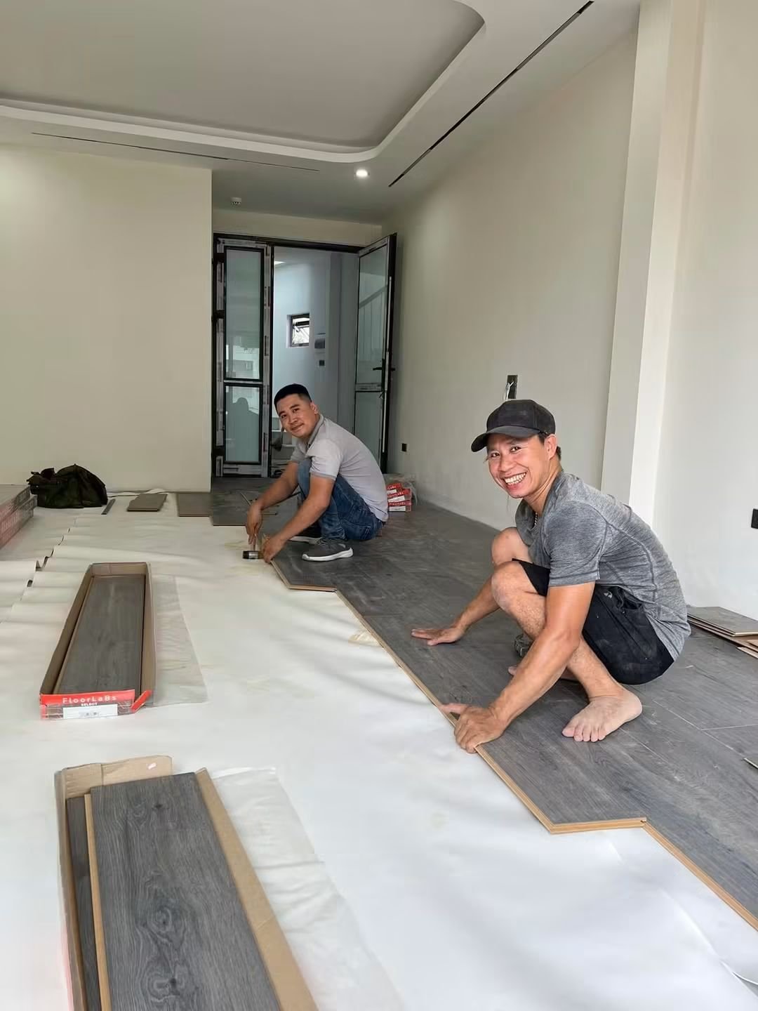 Hai thợ lắp sàn gỗ trong nhà