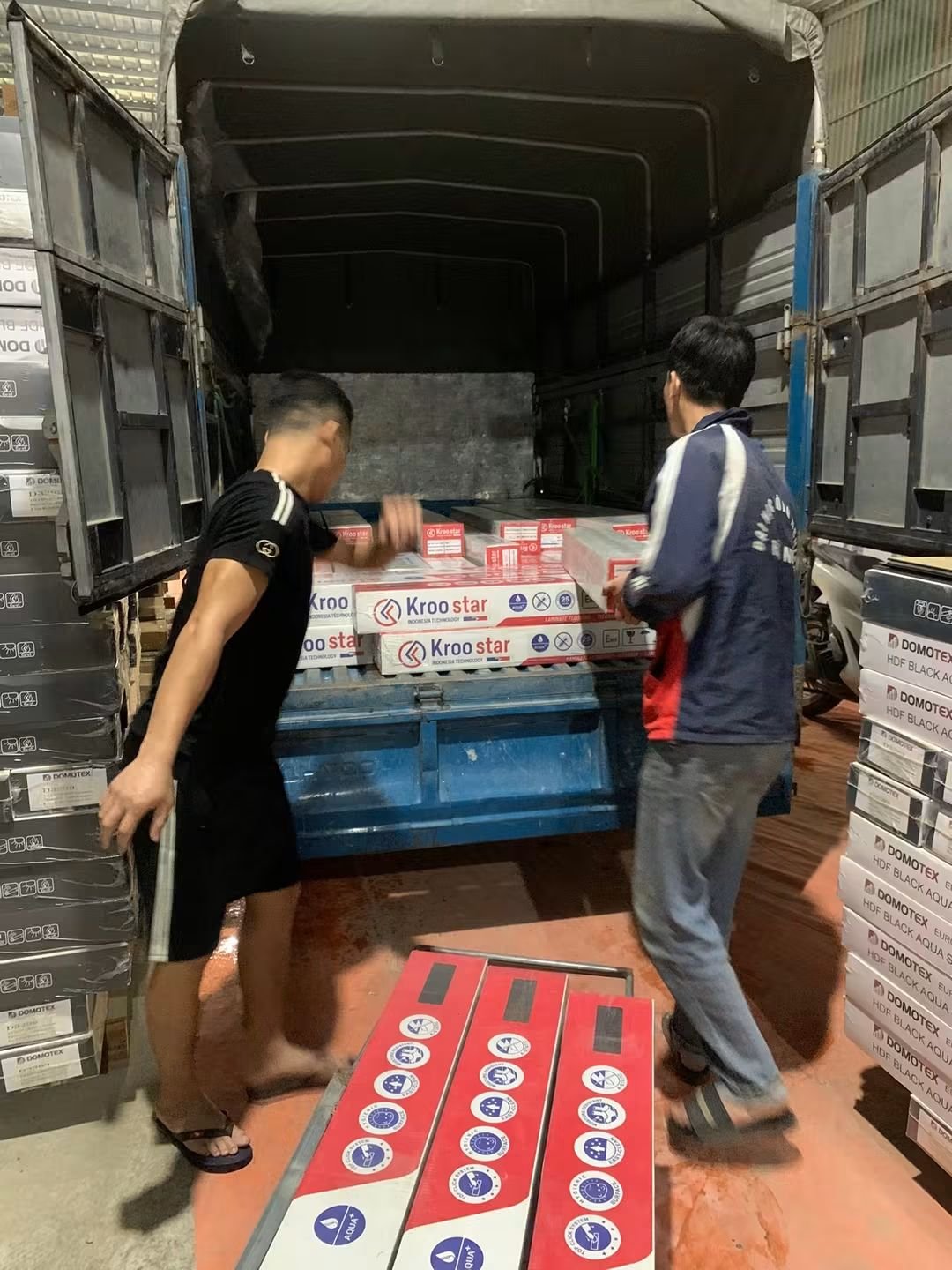 Hai nhân viên xếp hộp sàn gỗ lên thùng xe tải
