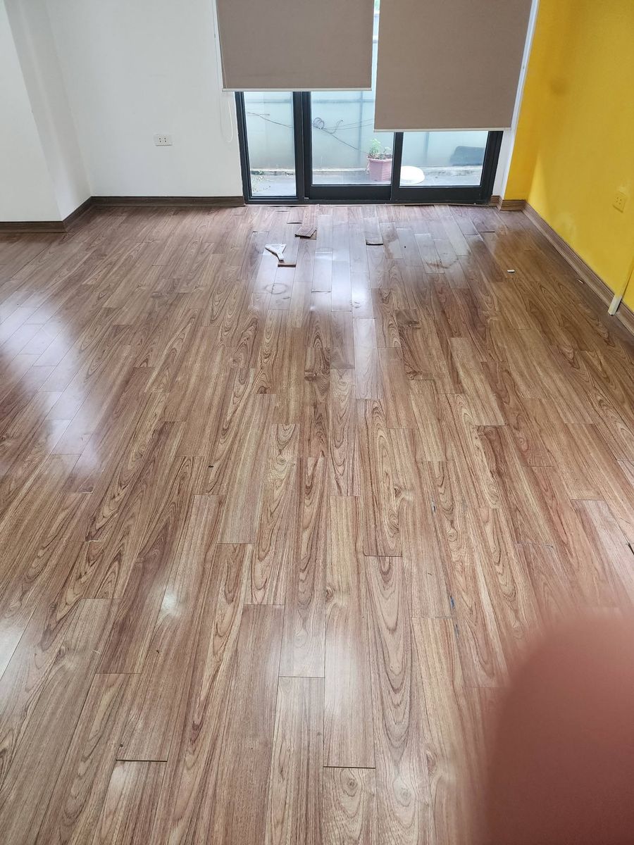 Thợ thay tấm sàn gỗ công nghiệp bị hư, vùng sàn đang thi công sửa